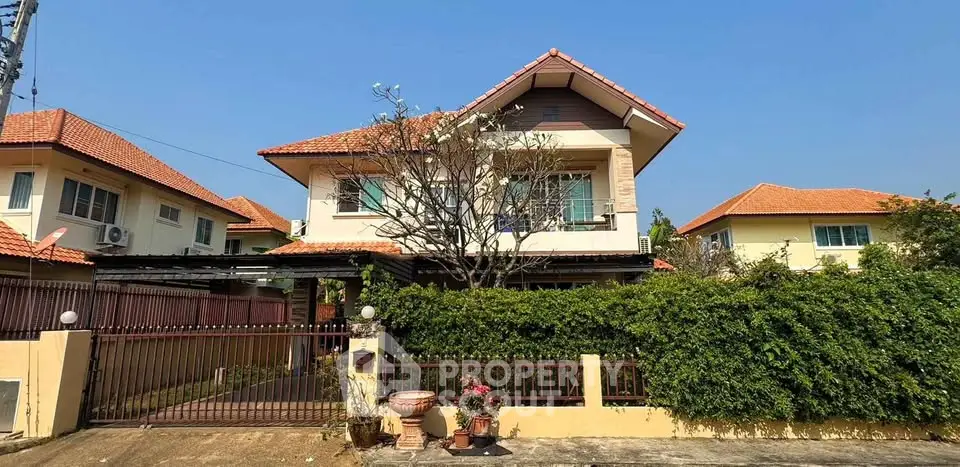 Charming two-story house with red-tiled roof and lush garden in a serene neighborhood.