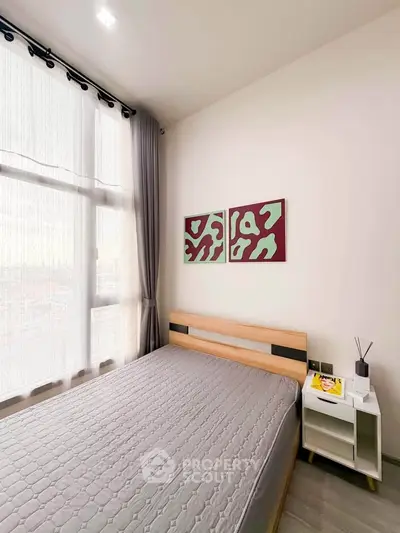 Modern bedroom with large window and stylish decor in a cozy apartment.