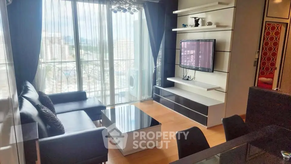 Modern living room with sleek furniture and large windows offering city views.