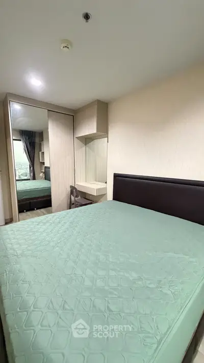 Modern bedroom with large bed, mirrored wardrobe, and built-in desk in stylish apartment.
