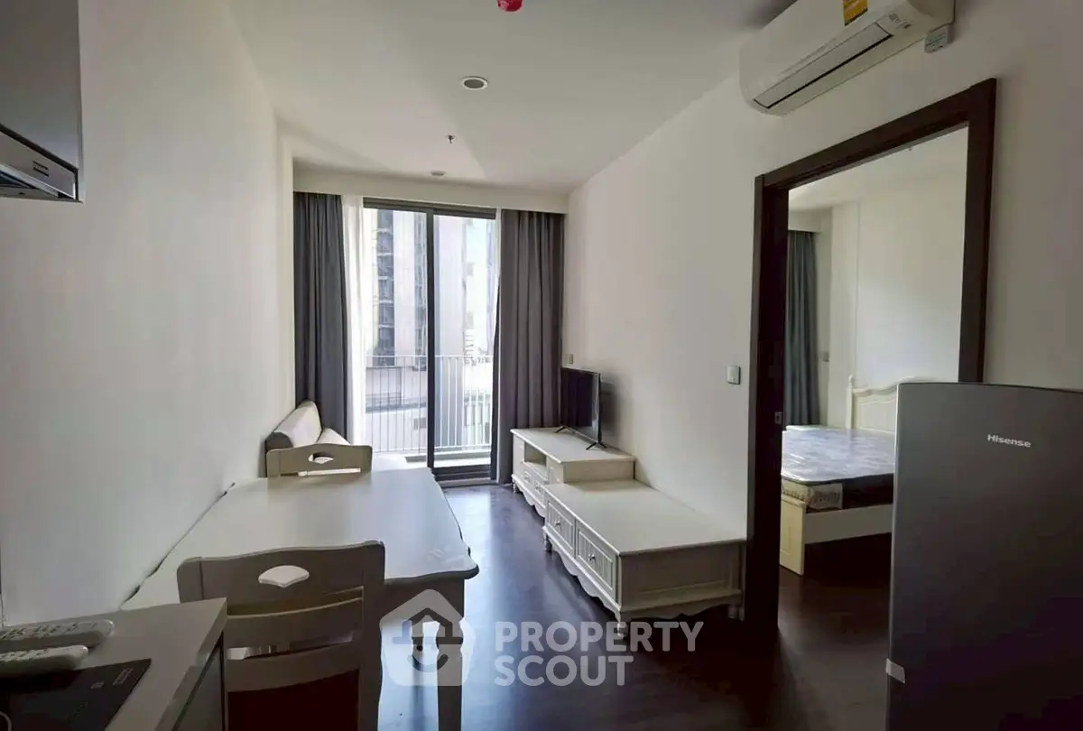 Modern apartment with open living area and balcony access, featuring sleek furniture and natural light.