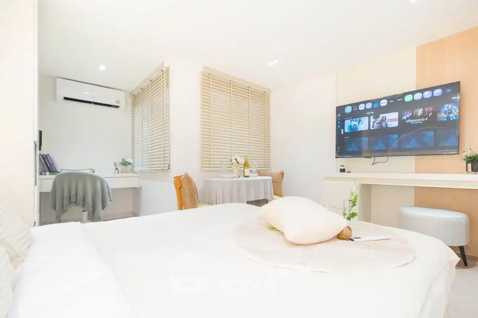 Bright and modern bedroom with stylish decor and wall-mounted TV, perfect for cozy living.