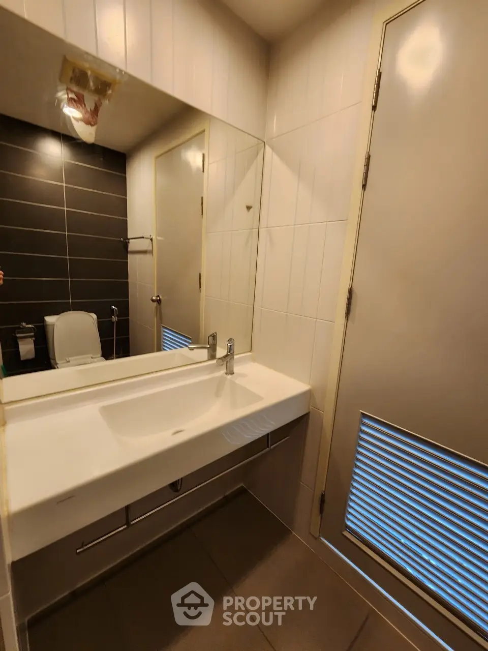 Modern bathroom with sleek sink and large mirror in contemporary apartment.