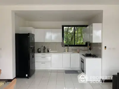 Modern kitchen with sleek white cabinets and black appliances in a bright open layout.