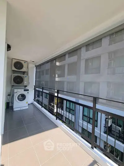 Spacious balcony with washing machine and modern building view