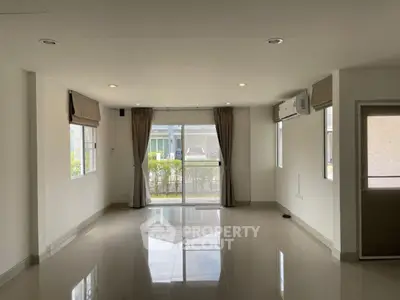Spacious unfurnished living room with large windows and glossy tiled floors