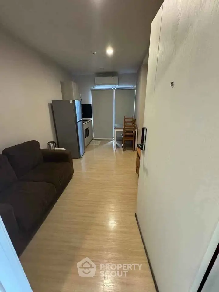 Cozy apartment interior with modern kitchen and living area, featuring wooden flooring and compact design.