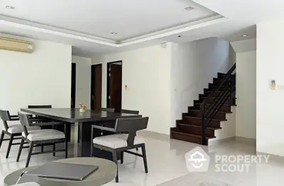 Spacious modern dining area with elegant staircase and stylish furniture