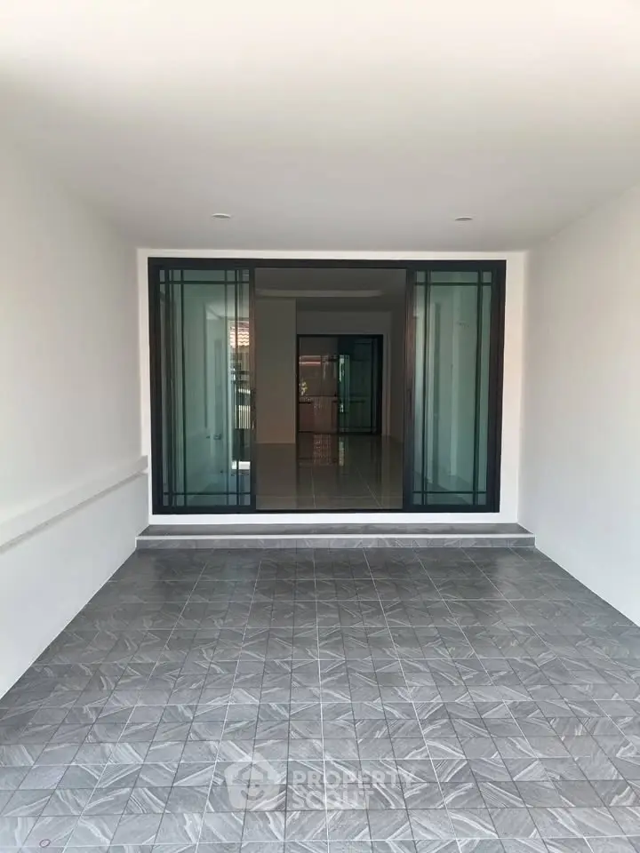 Spacious modern entrance with sleek sliding glass doors and elegant tiled flooring.