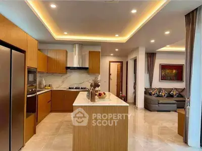Modern kitchen with open layout and stylish living room, featuring elegant lighting and contemporary decor.