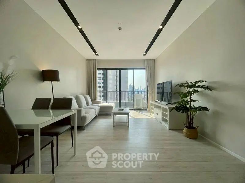 Spacious modern living room with balcony and city view, featuring sleek furniture and natural light.