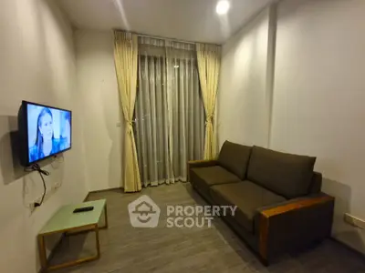 Modern living room with cozy sofa and wall-mounted TV, featuring elegant curtains and sleek flooring.