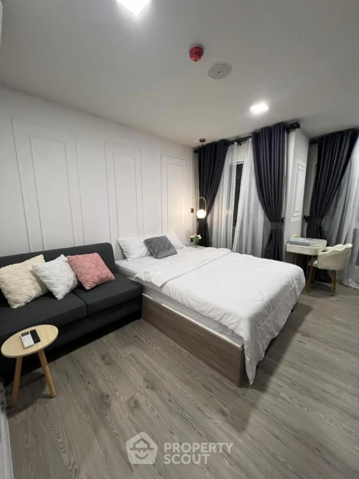 Modern bedroom with cozy bed, stylish sofa, and elegant curtains, perfect for relaxation and comfort.