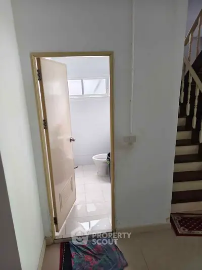 Cozy interior view featuring a small bathroom with a staircase nearby, ideal for compact living spaces.