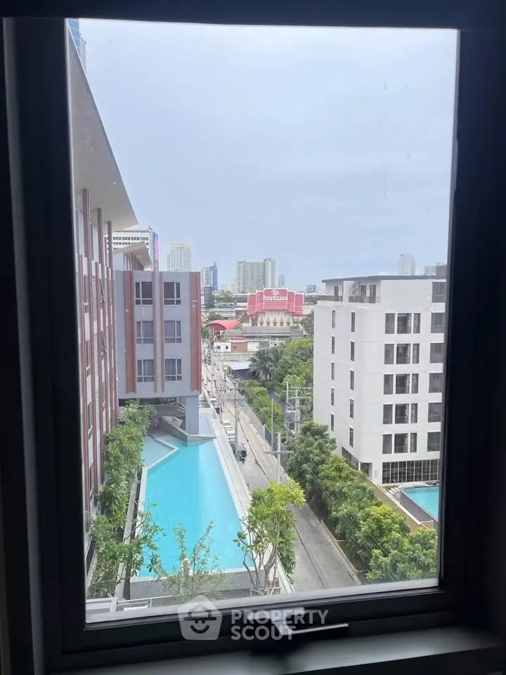 Stunning cityscape view from a modern apartment window overlooking a pool and urban skyline.