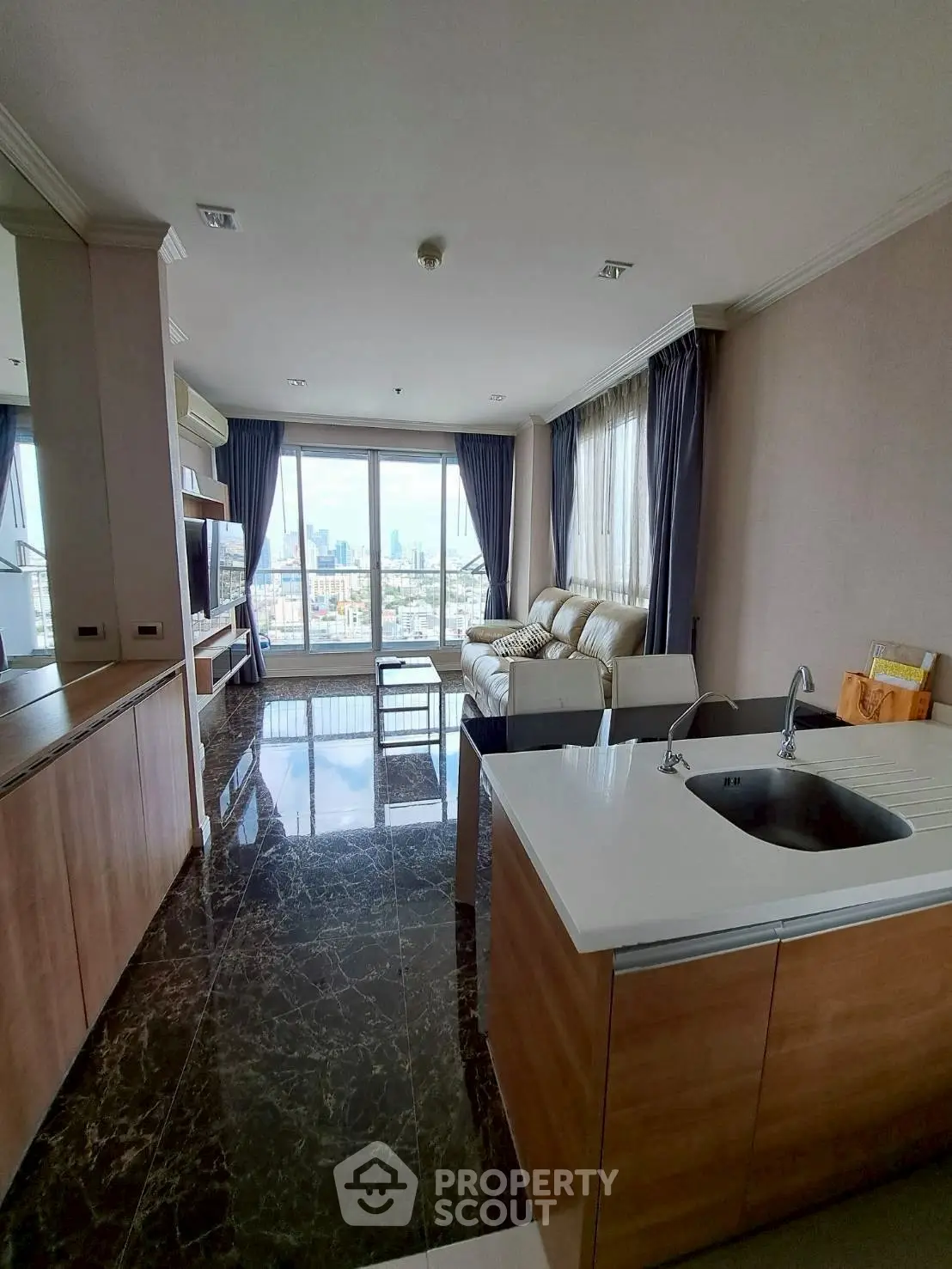 Modern living room with city view, sleek kitchen island, and luxurious furnishings.