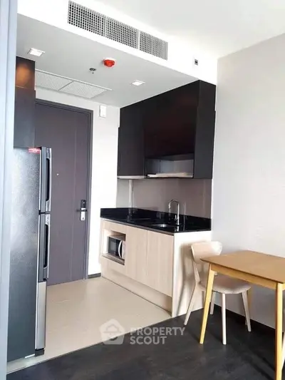 Modern compact kitchen with sleek cabinetry and integrated appliances in a stylish apartment.
