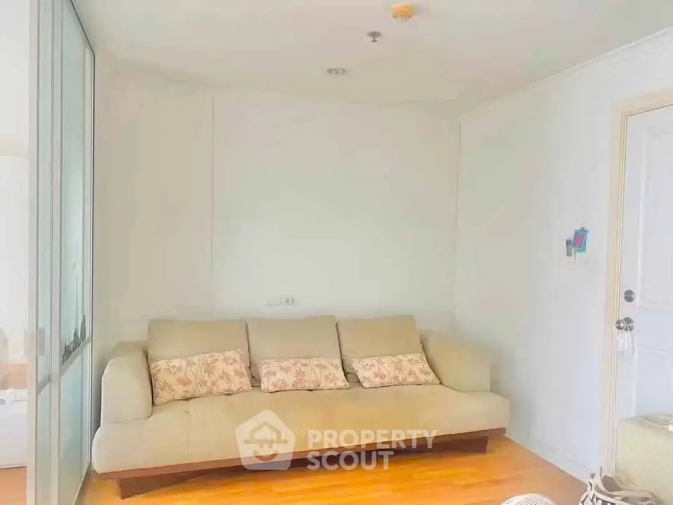 Cozy living room with beige sofa and wooden flooring, perfect for relaxation.