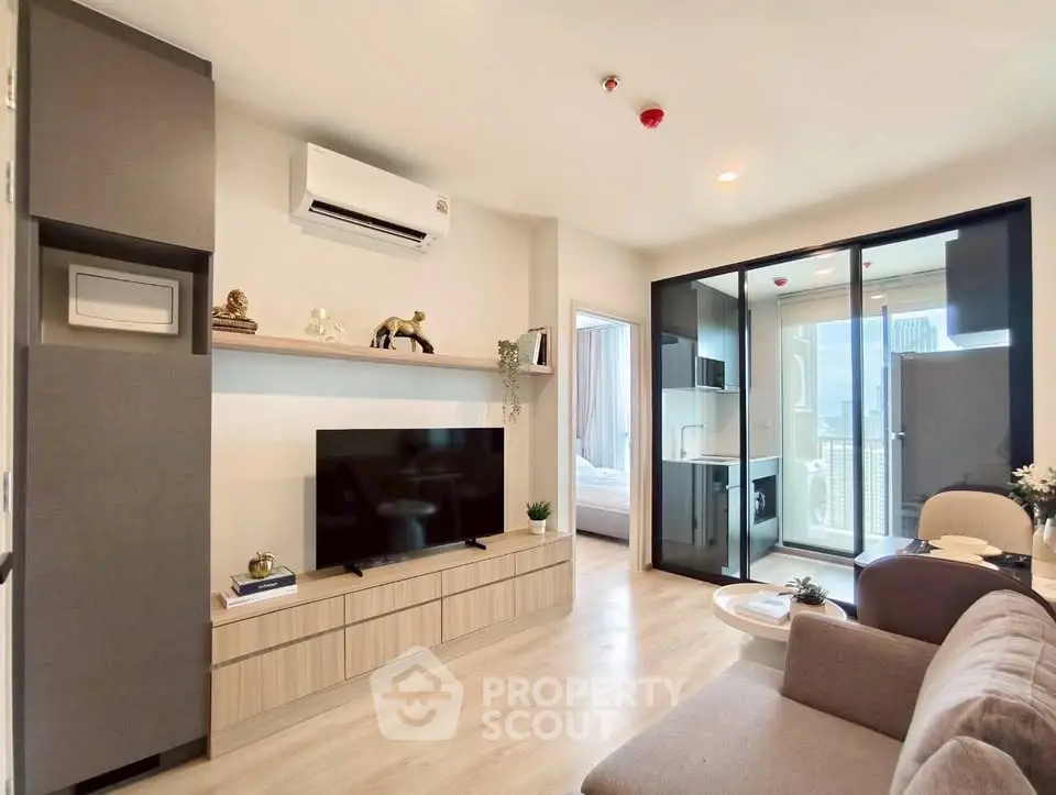Modern living room with sleek design, large TV, and glass doors leading to a balcony with city view.