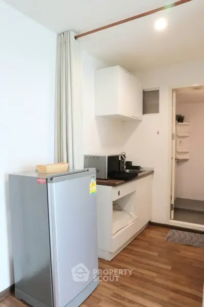 Compact kitchen with fridge and microwave in modern apartment