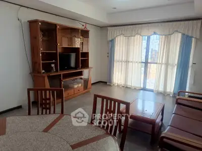 Spacious living room with wooden furniture and large window for natural light.
