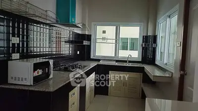 Modern kitchen with gas stove and ample natural light, featuring sleek black tile backsplash and spacious countertops.