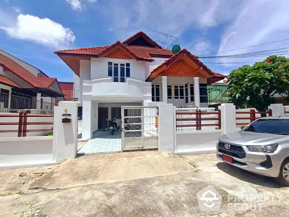 Charming two-story house with red roof and spacious driveway in a serene neighborhood.