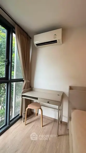 Cozy study nook with desk and chair by large window in modern apartment.