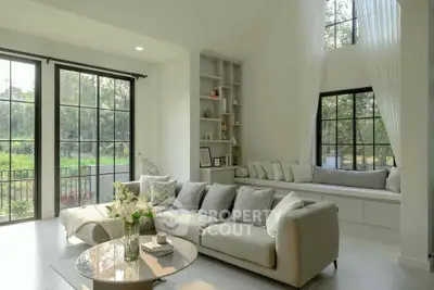 Spacious living room with large windows and elegant decor, offering a serene view of the garden.