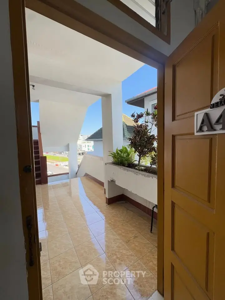 Inviting entrance with tiled flooring and lush greenery, offering a glimpse of the serene outdoor view.