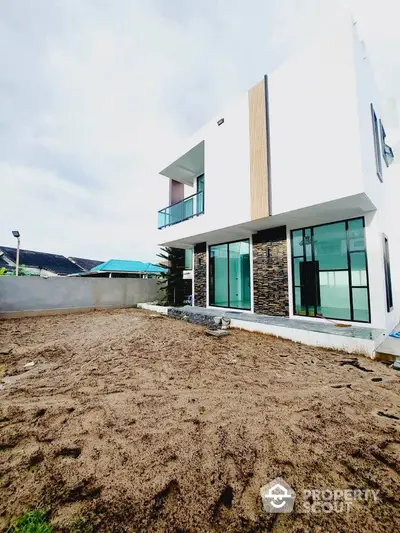 Modern two-story house with large windows and minimalist design in a spacious yard.