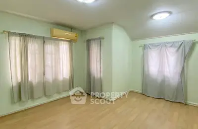 Spacious bedroom with wooden flooring and natural light