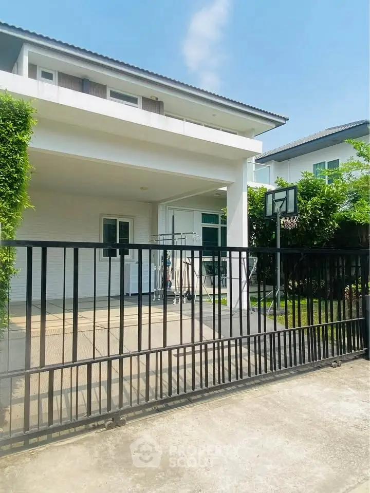Modern two-story house with gated driveway and basketball hoop