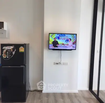 Modern living space with mounted TV and sleek black fridge