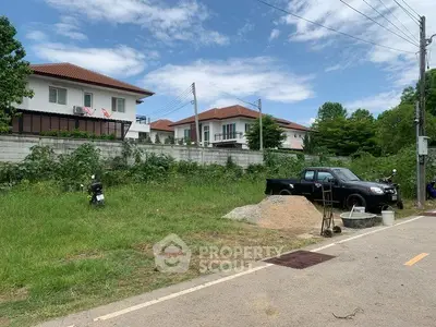 Vacant land plot with potential for development in a residential area with nearby houses.