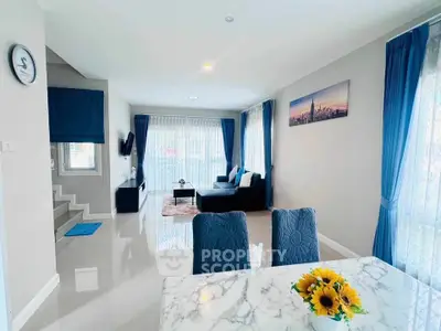 Elegant living room with modern decor and marble dining table, featuring blue accents and natural light.