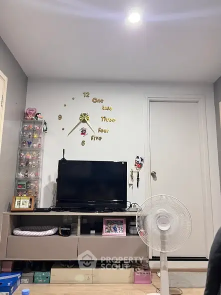 Cozy living room with modern decor and wall-mounted TV, featuring a unique wall clock design.