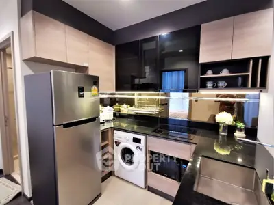 Modern kitchen with sleek appliances and integrated washing machine in stylish apartment.