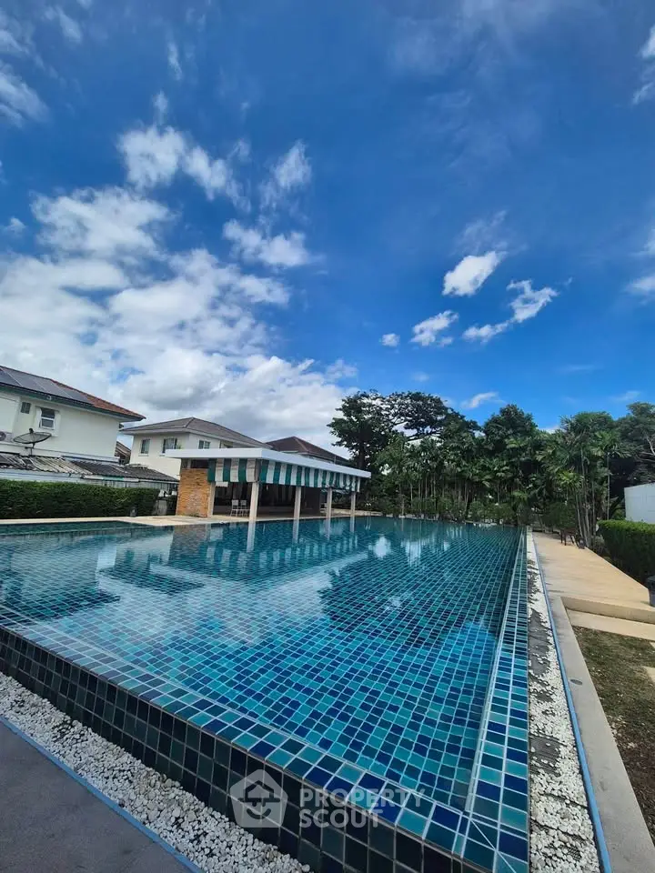 Stunning residential pool with clear blue skies and lush greenery, perfect for relaxation and leisure.