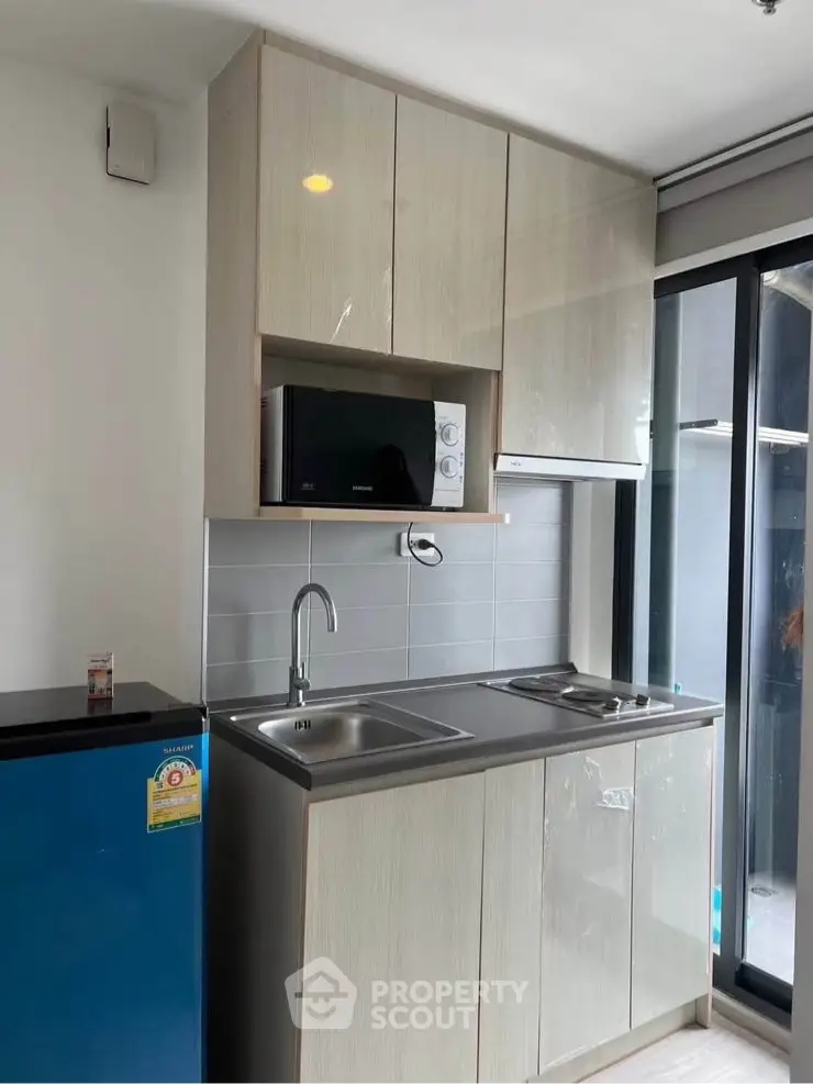 Modern compact kitchen with sleek cabinetry and appliances in a bright apartment.