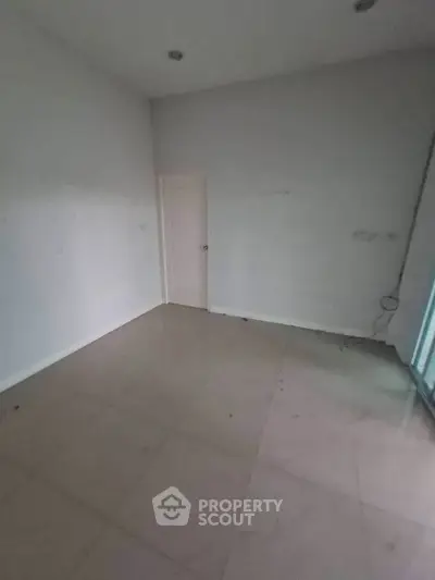 Spacious empty room with tiled flooring and white walls, ideal for customization.