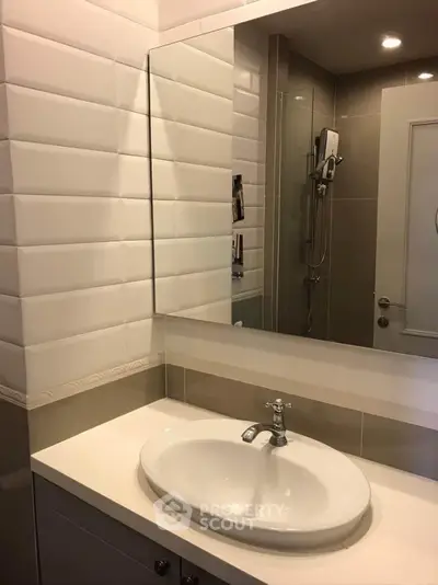 Modern bathroom with sleek sink and large mirror in contemporary apartment.