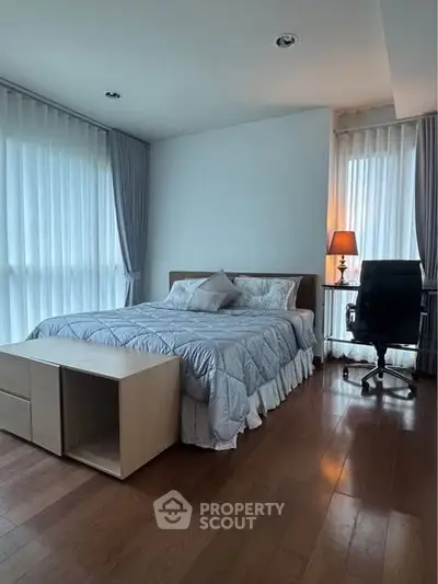 Spacious bedroom with elegant decor and natural light, featuring a cozy bed and a modern workspace.