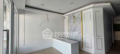 Modern commercial space with sleek white interior and marble accent wall, ideal for business setup.