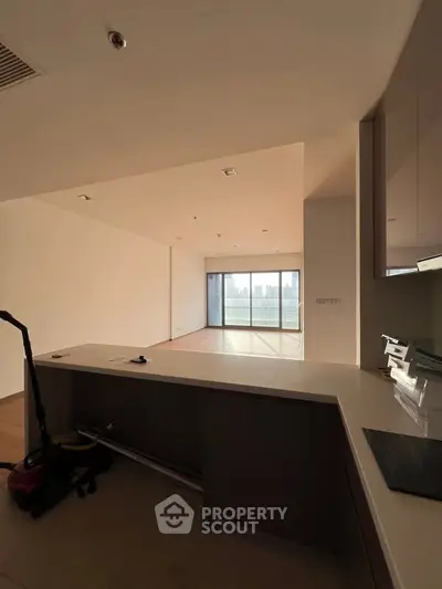 Spacious open-plan living area with large windows and city view, ideal for modern urban living.