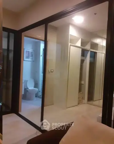 Modern apartment interior with glass partition and bathroom view, showcasing sleek design and contemporary style.