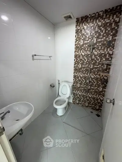 Modern bathroom with sleek white fixtures and stylish mosaic tile accent wall.