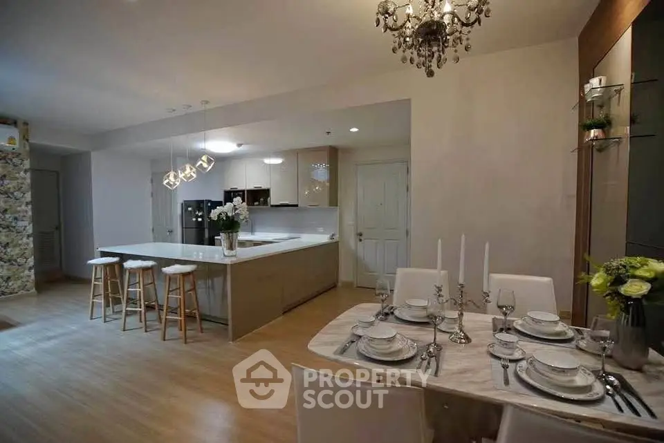 Luxurious open-layout kitchen and dining area with elegant chandelier and modern decor.