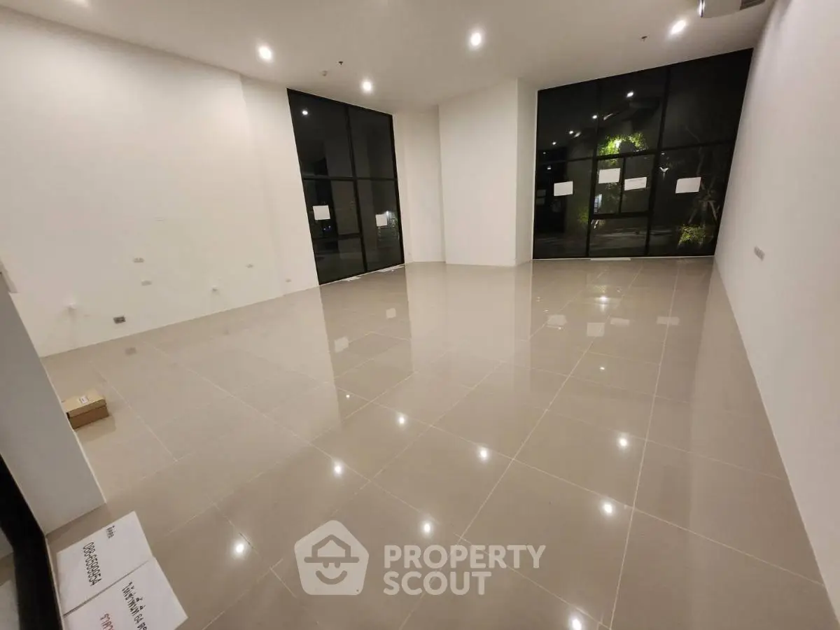 Spacious empty room with large windows and glossy tiled floor