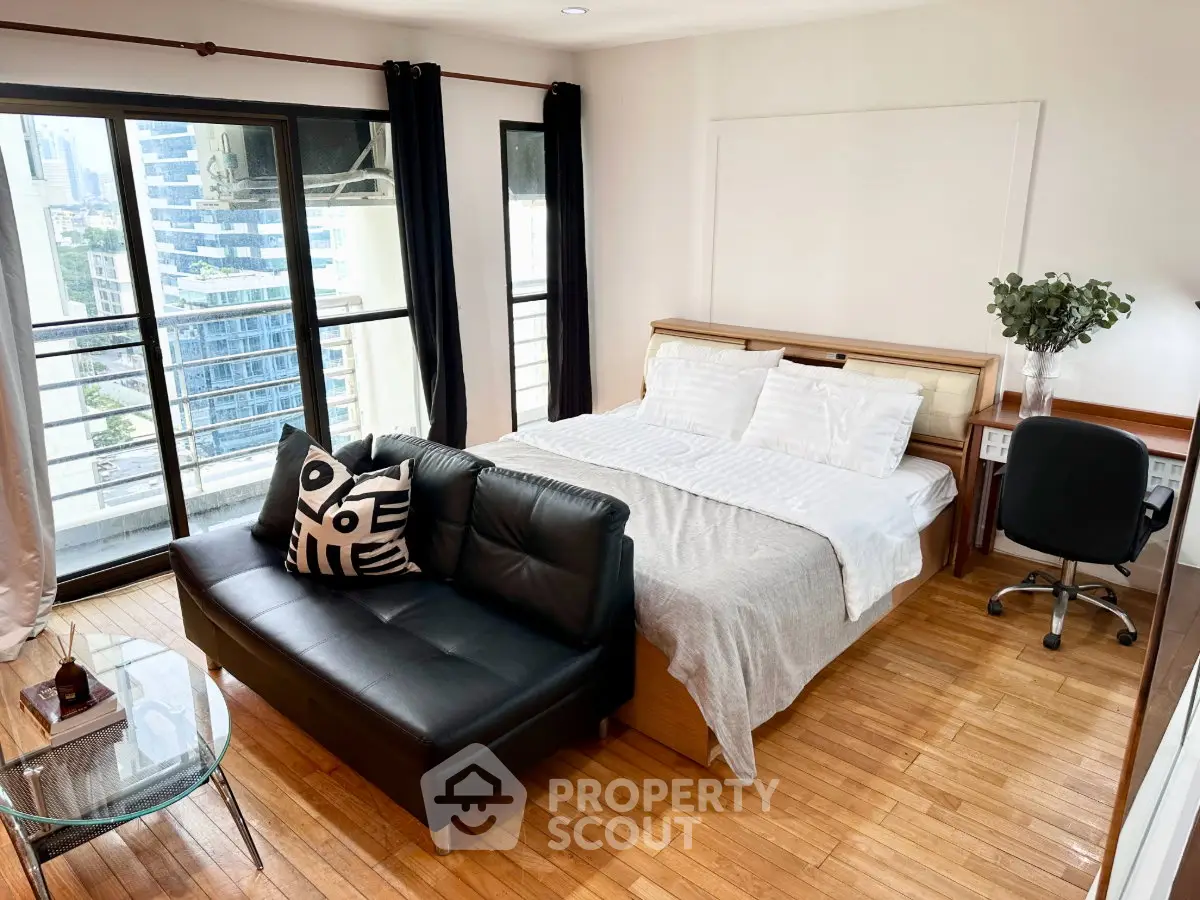Spacious bedroom with city view, featuring a cozy bed, stylish sofa, and modern decor.